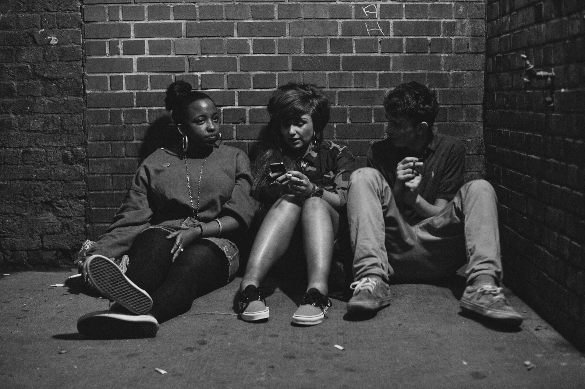 a group of people sitting on a bench talking on a cell phone